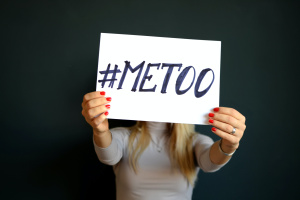 Frau hält Schild mit "#metoo" in die Kamera