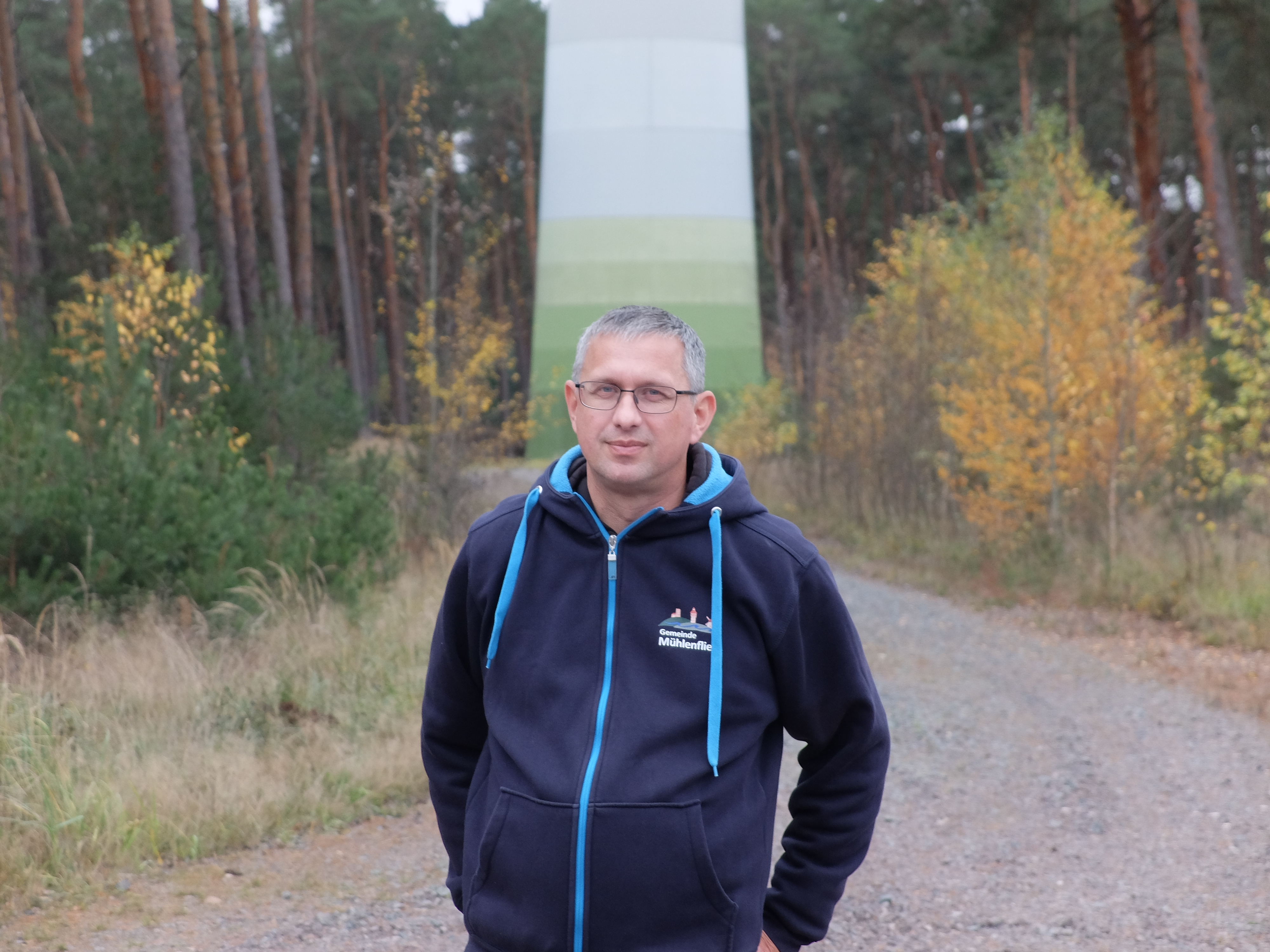 ein Mann steht vor einem Windrad im Wald